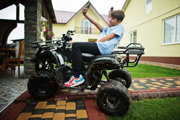 Ragazzo in quad ATV a quattro ruote motrici con telefono cellulare.