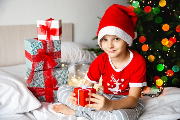 ragazzo in santa hat detiene il regalo di capodanno