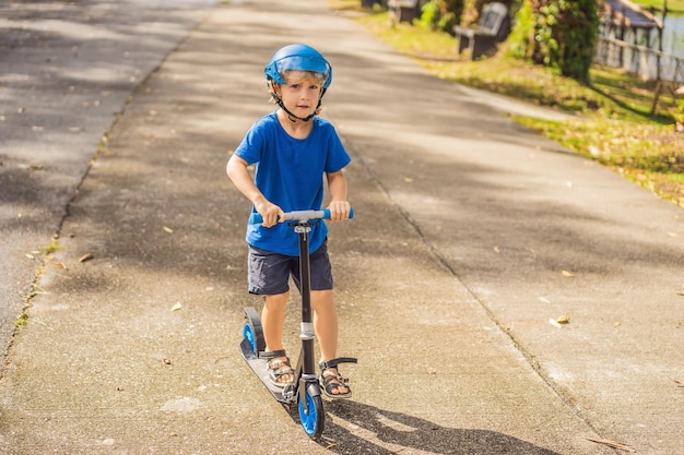 Ragazzo in sella a scooter all'aperto nell'estate del parco I bambini sono felici di giocare all'aperto