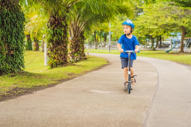 Ragazzo in sella a scooter all'aperto nell'estate del parco I bambini sono felici di giocare all'aperto