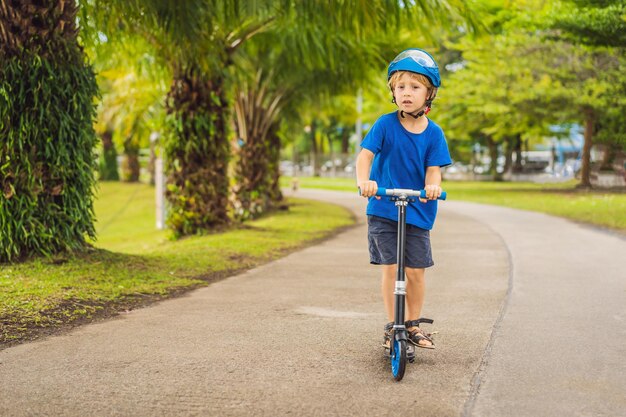 Ragazzo in sella a scooter all'aperto nell'estate del parco I bambini sono felici di giocare all'aperto