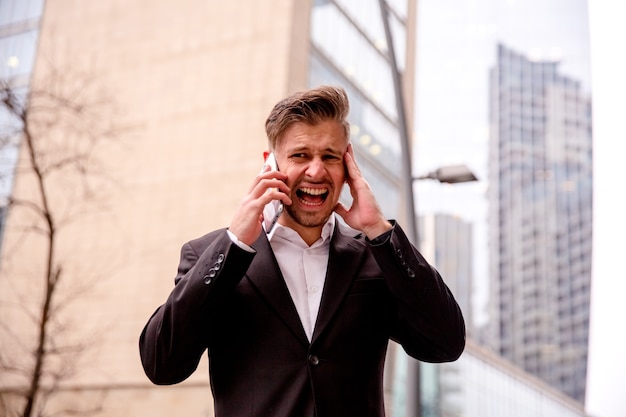 Ragazzo in un vestito che parla al telefono arrabbiato