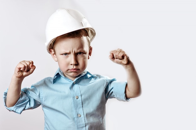 Ragazzo in una camicia leggera e casco Builder mostra come è forte e fiducioso