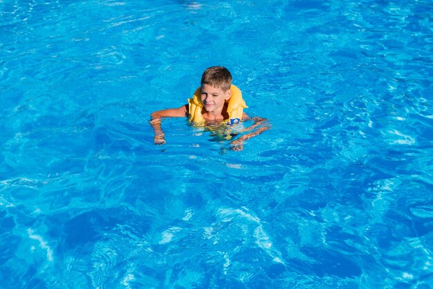 Ragazzo in una giacca gonfiabile in piscina in estate