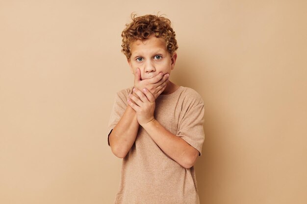 Ragazzo in una maglietta beige con capelli ricci in posa