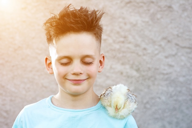 Ragazzo in una maglietta blu con un soffice pollo chiuse gli occhi e sognava uno sfocato.