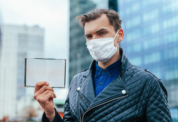 Ragazzo in una maschera protettiva che mostra il suo passaporto aperto