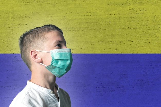 Ragazzo in una mascherina medica sul suo viso su sfondo di bandiera Ucraina.