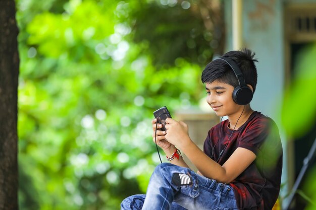 Ragazzo indiano che ascolta musica o che impara sul telefono cellulare