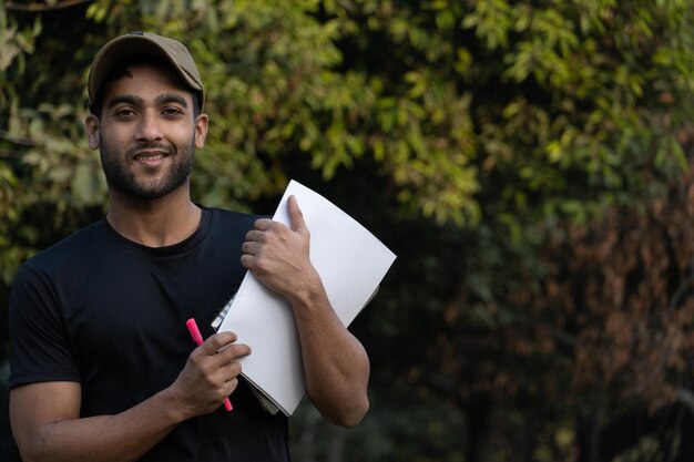 Ragazzo indiano che ha carta penna con libri