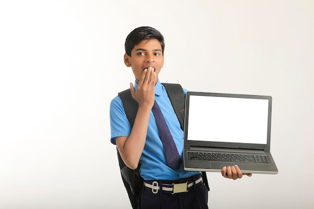 Ragazzo indiano della scuola che mostra lo schermo del computer portatile su fondo bianco