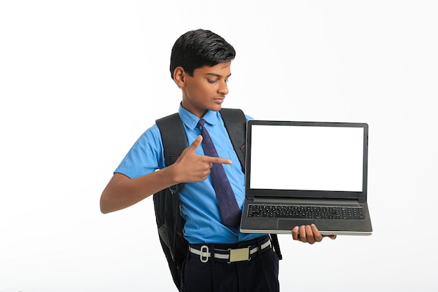 Ragazzo indiano della scuola che mostra lo schermo del computer portatile su fondo bianco.