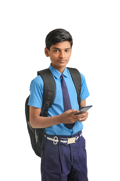 Ragazzo indiano della scuola che utilizza smartphone su priorità bassa bianca