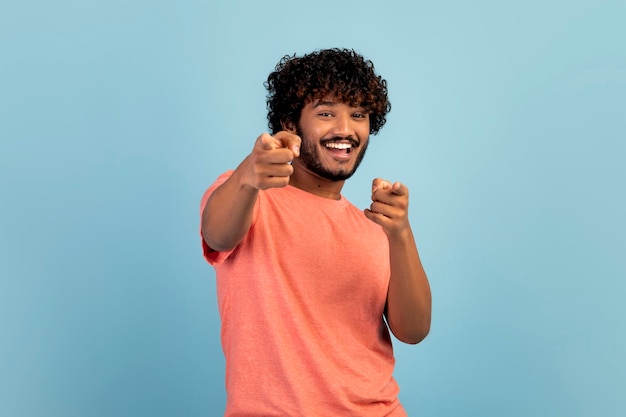 Ragazzo indù positivo che punta alla telecamera e sorridente