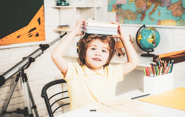 Ragazzo intelligente carino felice con il processo educativo del libro poco pronto a studiare i bambini a scuola