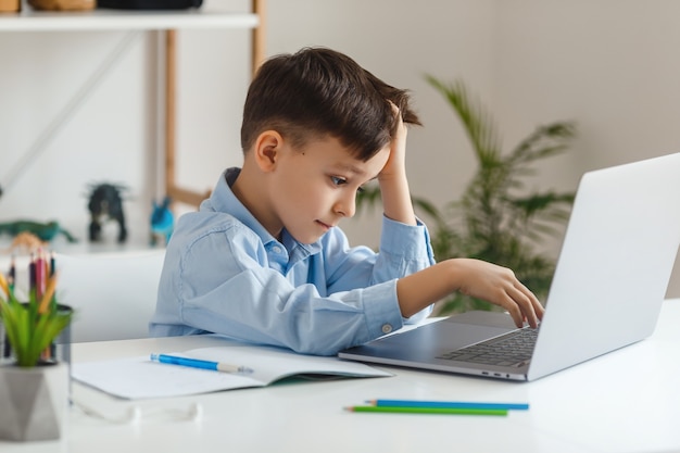 Ragazzo intelligente che fa i compiti utilizzando laptop e internet