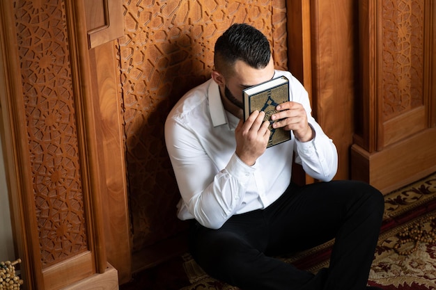Ragazzo musulmano attraente che bacia il Corano