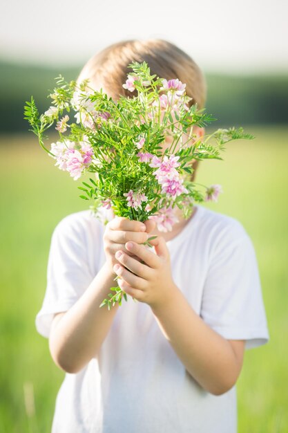 Ragazzo nascosto dal bouquet di fiori primaverili Concetto di festa della mamma