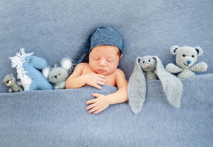 Foto ragazzo neonato sveglio che si trova sotto la coperta blu