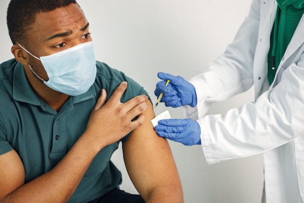 Ragazzo nero in maschera facciale che tiene un poster con le parole vaccinazione salva vite