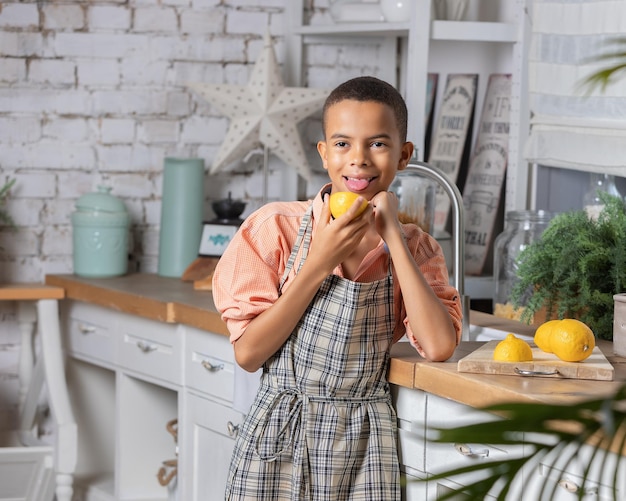 Ragazzo nero ragazzo che cucina limone fresco in cucina a casa bambino africano che si prepara sul tavolo