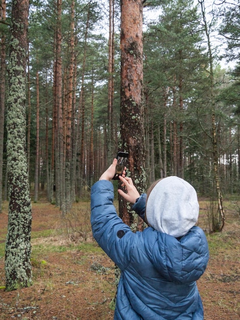 Ragazzo non identificato con una giacca blu scatta foto con lo smartphone nel parco
