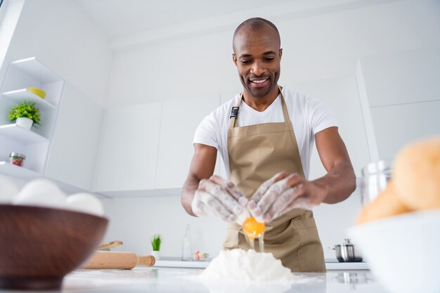 ragazzo pasticcere che fa pane fresco e morbido che impasta le uova di farina culinaria nella moderna cucina interna