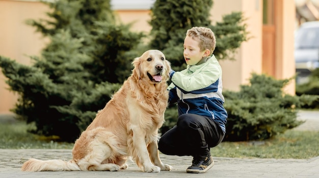 Ragazzo preteen con cane golden retriever seduto all'aperto Bambino bambino con animale domestico doggy in strada