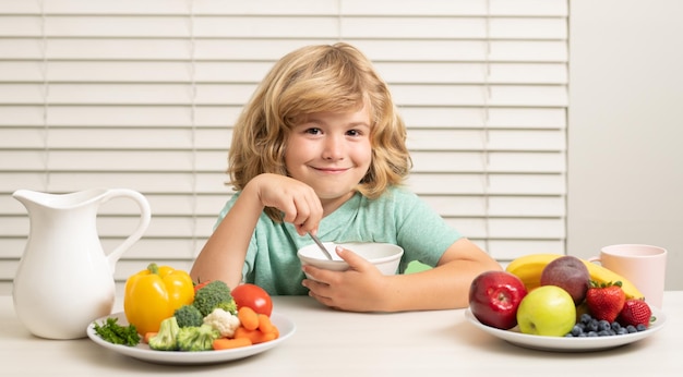 Ragazzo preteen del bambino che mangia la colazione sana delle verdure dell'alimento con la frutta e la verdura del latte m