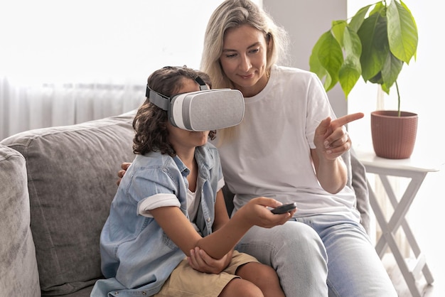 Ragazzo ragazzo che indossa l'auricolare per realtà virtuale con sua madre occhiali vr in soggiorno a casa divertendosi
