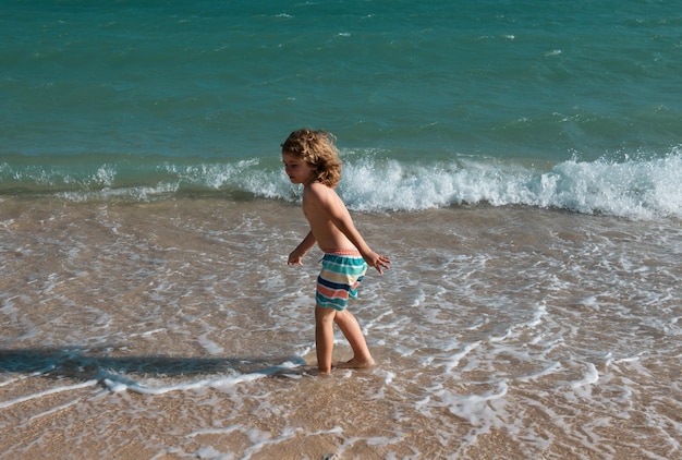 Ragazzo ragazzo che salta nelle onde del mare salta in acqua il mare spruzza le vacanze estive dei bambini