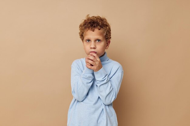 Ragazzo riccio in un maglione blu in posa divertente infanzia inalterata