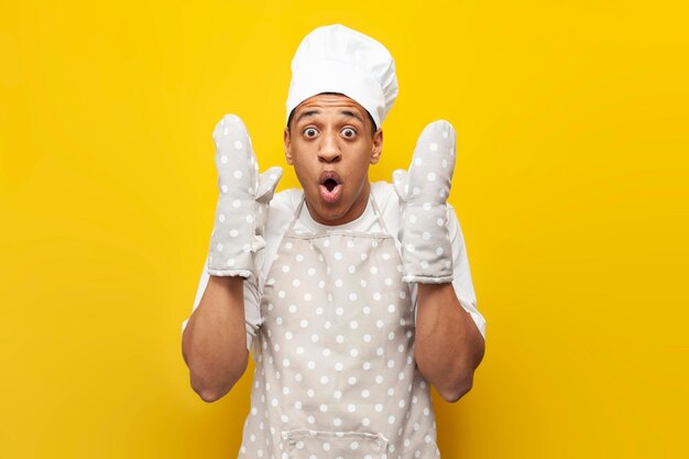 ragazzo scioccato cuoco afroamericano in uniforme è sorpreso su sfondo giallo isolato