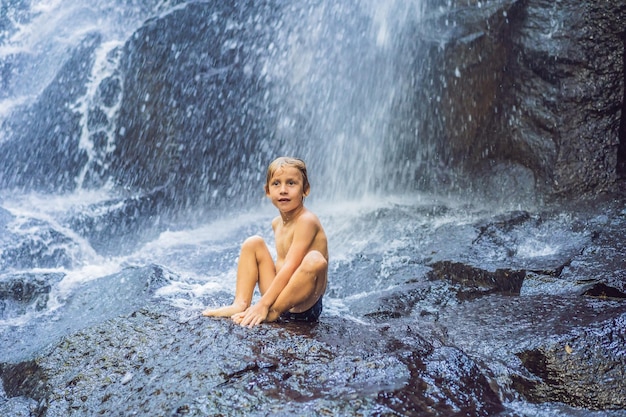 Ragazzo seduto in acqua alla cascata Viaggiare con il concetto di bambini Cosa fare con i bambini Luogo adatto ai bambini