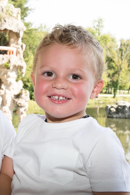 Ragazzo seduto in panchina vicino al lago al parco ridendo