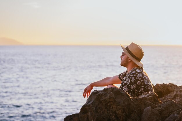 Ragazzo seduto rilassato guardando l'orizzonte in spiaggia