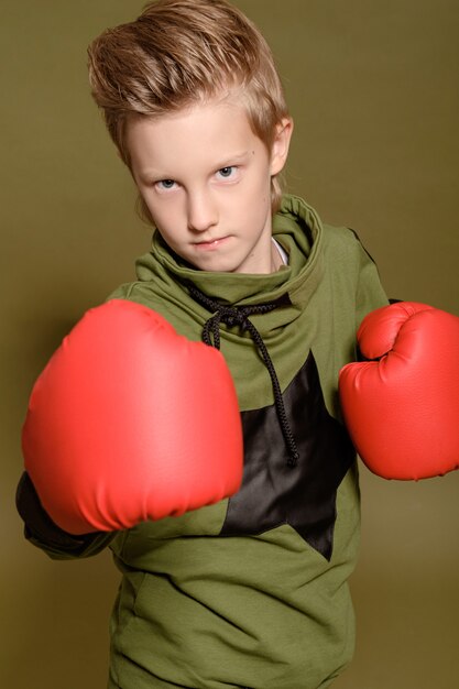 Ragazzo serio su uno sfondo verde in guantoni da boxe rossi