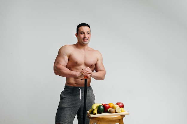 Ragazzo sexy vegano con un torso nudo in posa in studio accanto alla frutta. Dieta. Dieta sana