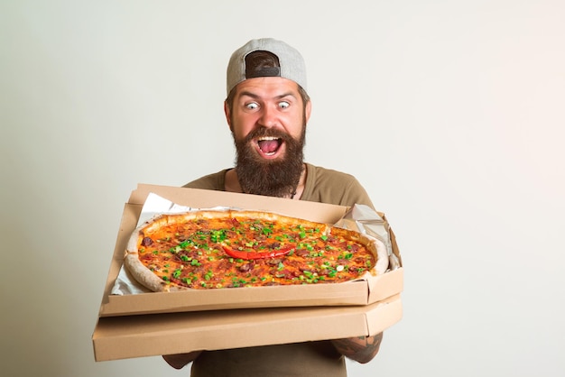 Ragazzo soddisfatto in maglietta gusta una gustosa pizza Cibo italiano Cena per studenti Concetto di consegna della pizza