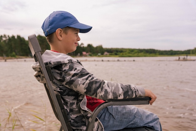 Ragazzo solitario seduto sulla riva di un lago tranquillo che contempla la natura serenità