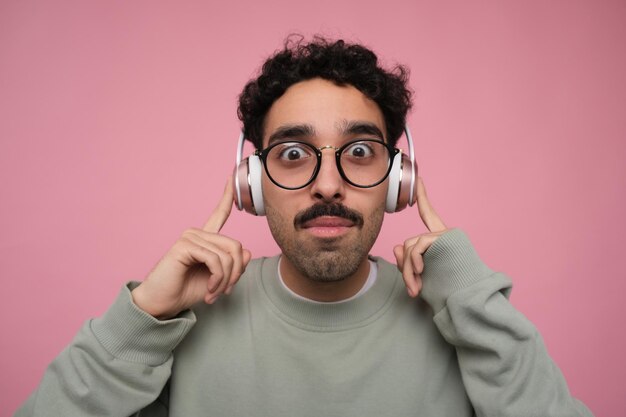 ragazzo sorpreso e scioccato che ascolta musica in cuffia che punta alle orecchie