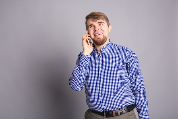 Ragazzo sorridente che parla su un telefono cellulare sul muro grigio