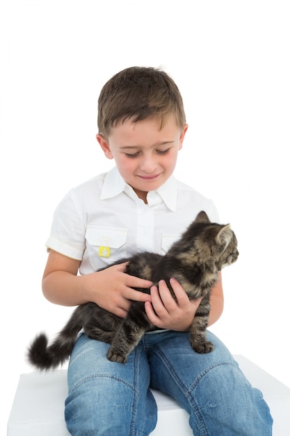 Ragazzo sorridente che si siede stringendo a sé un gattino grigio