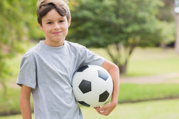 Ragazzo sorridente che tiene un pallone da calcio nel parco