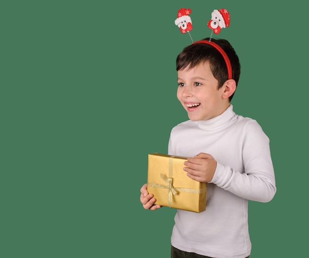 Ragazzo sorridente che tiene una scatola regalo d'oro su sfondo verde