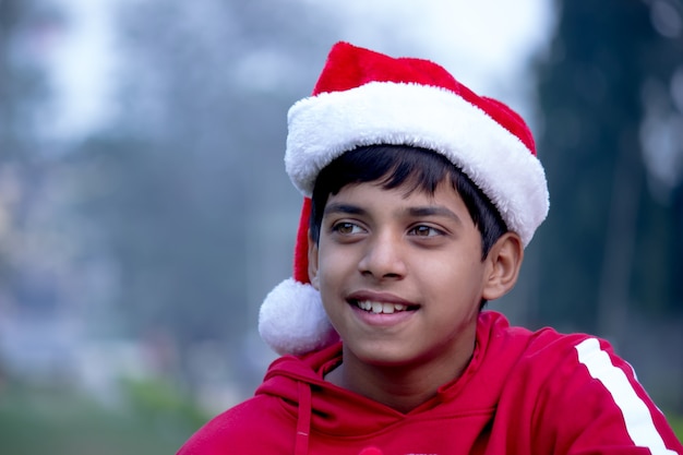 Ragazzo sorridente con un cappello rosso di Babbo Natale su uno sfondo morbido