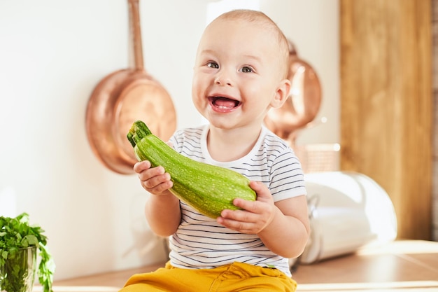 Ragazzo sorridente del bambino con una zucchina nelle sue mani