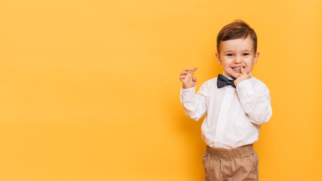 Ragazzo sorridente del bambino felice del bambino sulla parete gialla con lo spazio della copia.