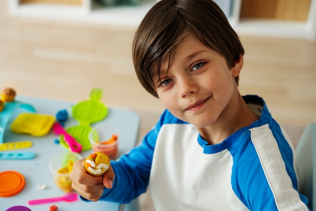 Ragazzo sorridente di vista laterale che gioca all'interno