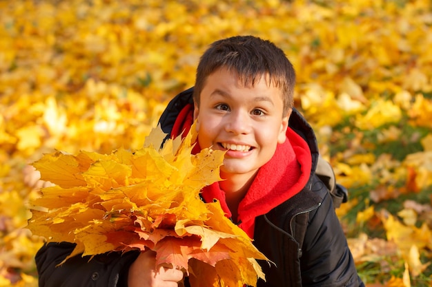 Ragazzo sorridente felice con foglie d'autunno